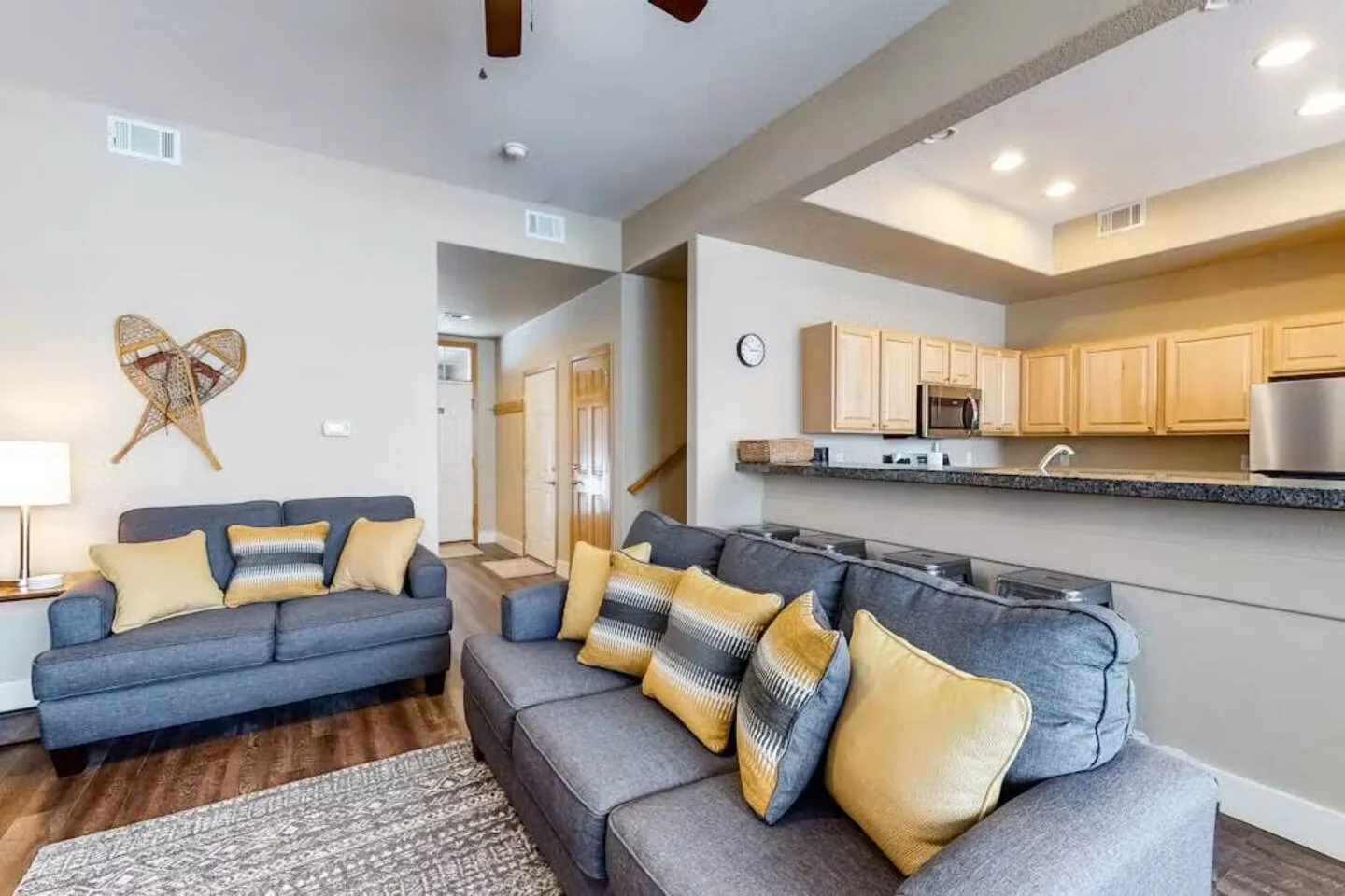 North Pond Retreat, Gray sofas in the living room with yellow cushions beside the open kitchen, waterfront vacation rental in Silverthorne, Colorado