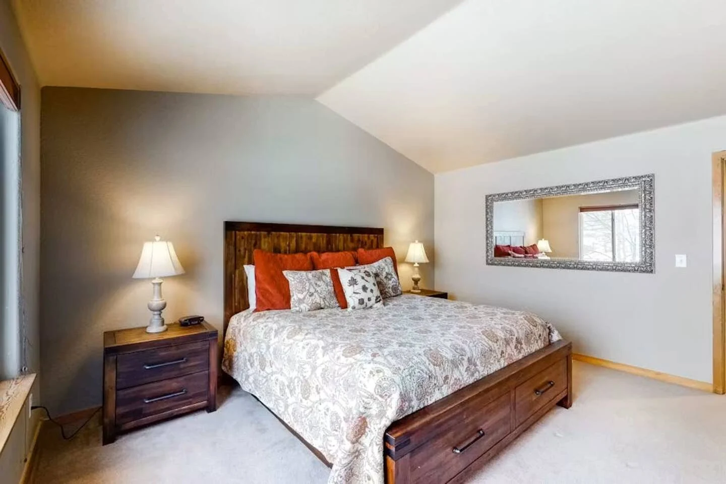 North Pond Retreat, King bed with a wood headboard, patterned quilt, bedside lamps, and wall mirror, waterfront vacation rental in Silverthorne, Colorado