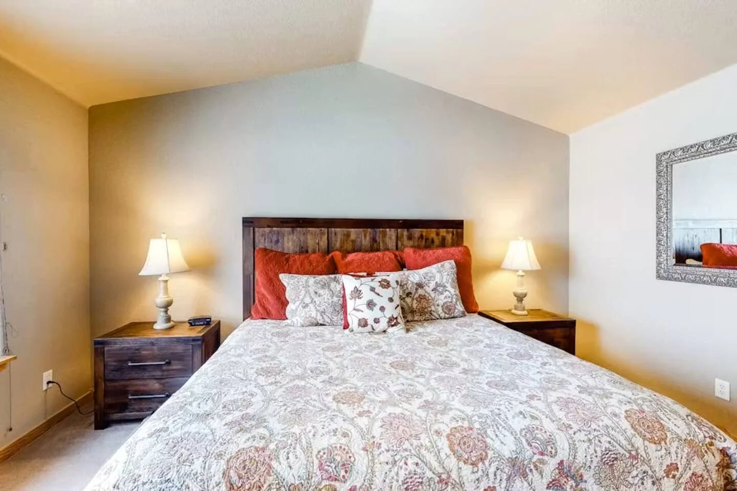 North Pond Retreat, King bed with patterned bedding and red pillows between softly lit nightstands, waterfront vacation rental in Silverthorne, Colorado
