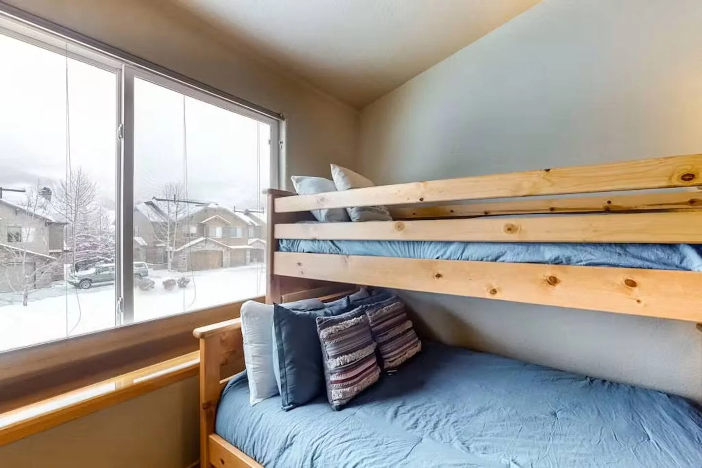 North Pond Retreat, Wood bunk bed with blue pillows beside the bright bedroom window, waterfront vacation rental in Silverthorne, Colorado