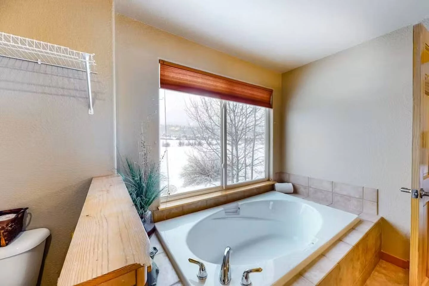 North Pond Retreat, Bathtub with wood trim beside a window looking toward trees, waterfront vacation rental in Silverthorne, Colorado