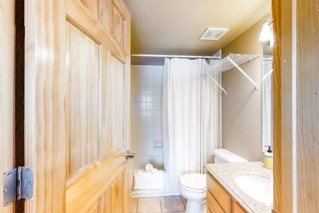 North Pond Retreat, Bathroom with a shower curtain, vanity mirror, and warm wood cabinetry, waterfront vacation rental in Silverthorne, Colorado