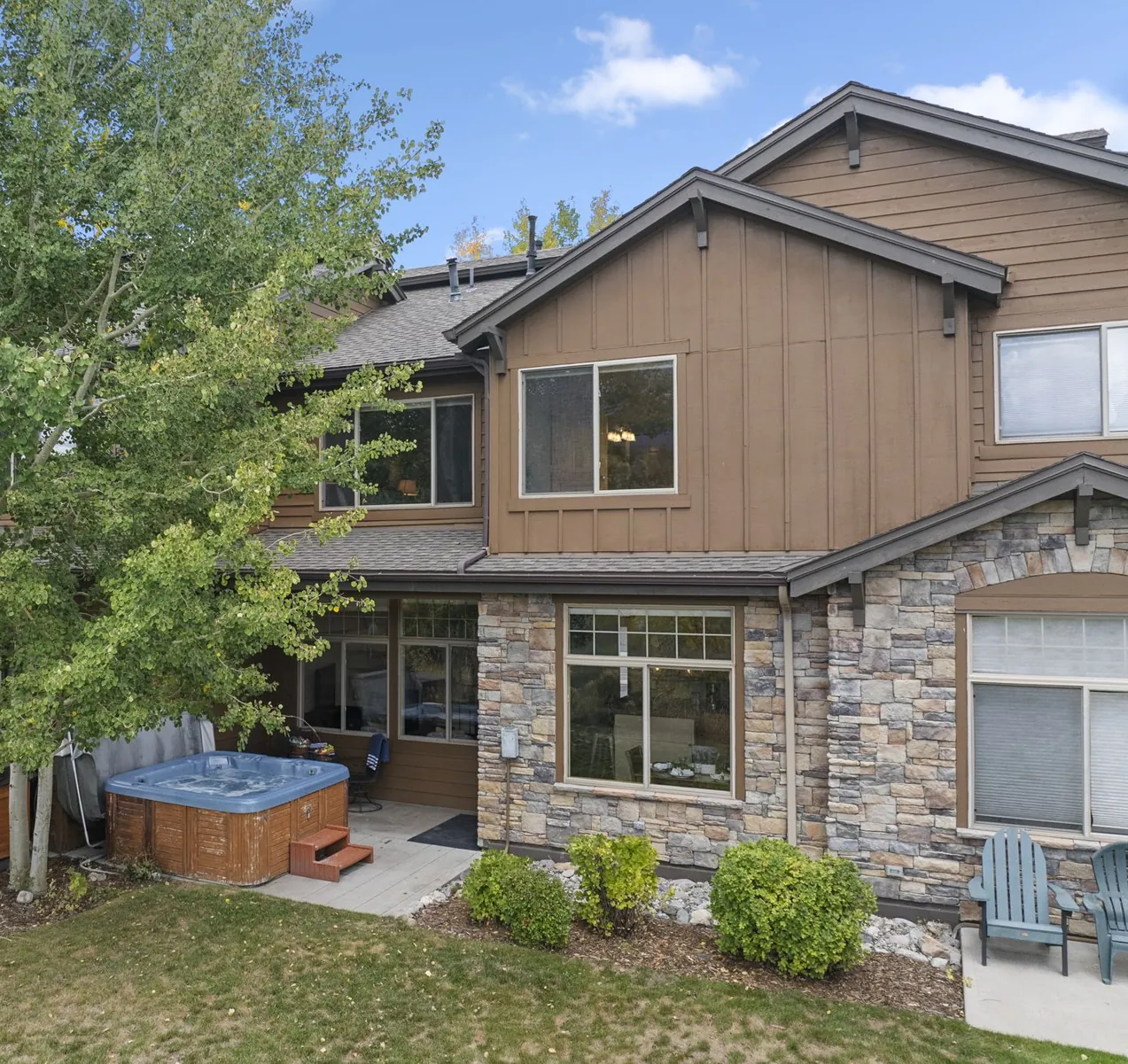 North Pond Retreat, Elevated view of the home's wood and stone exterior, patio, hot tub, and lawn, waterfront vacation rental in Silverthorne, Colorado