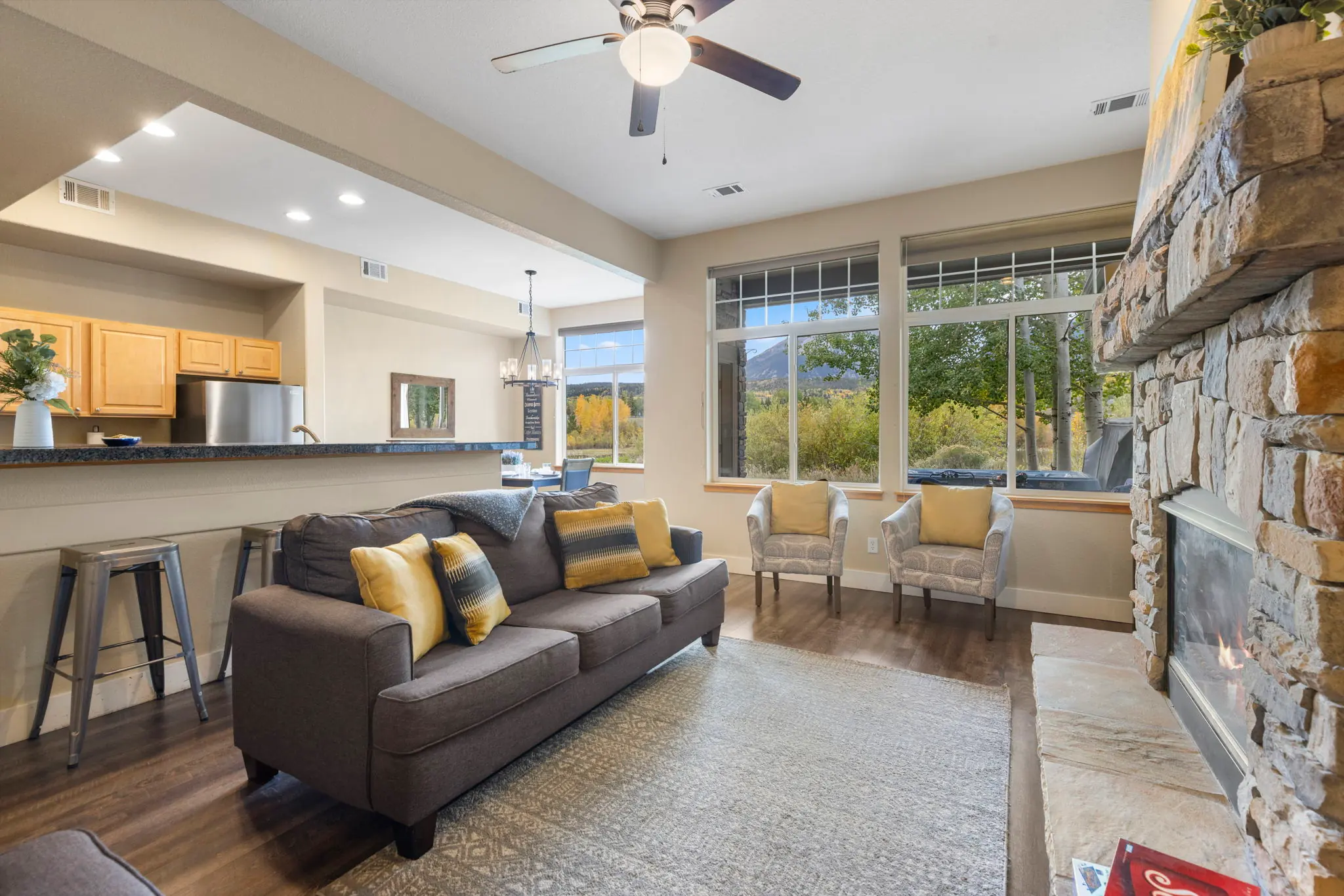 North Pond Retreat, Gray sofa with golden cushions beside the fireplace and large living room windows, waterfront vacation rental in Silverthorne, Colorado