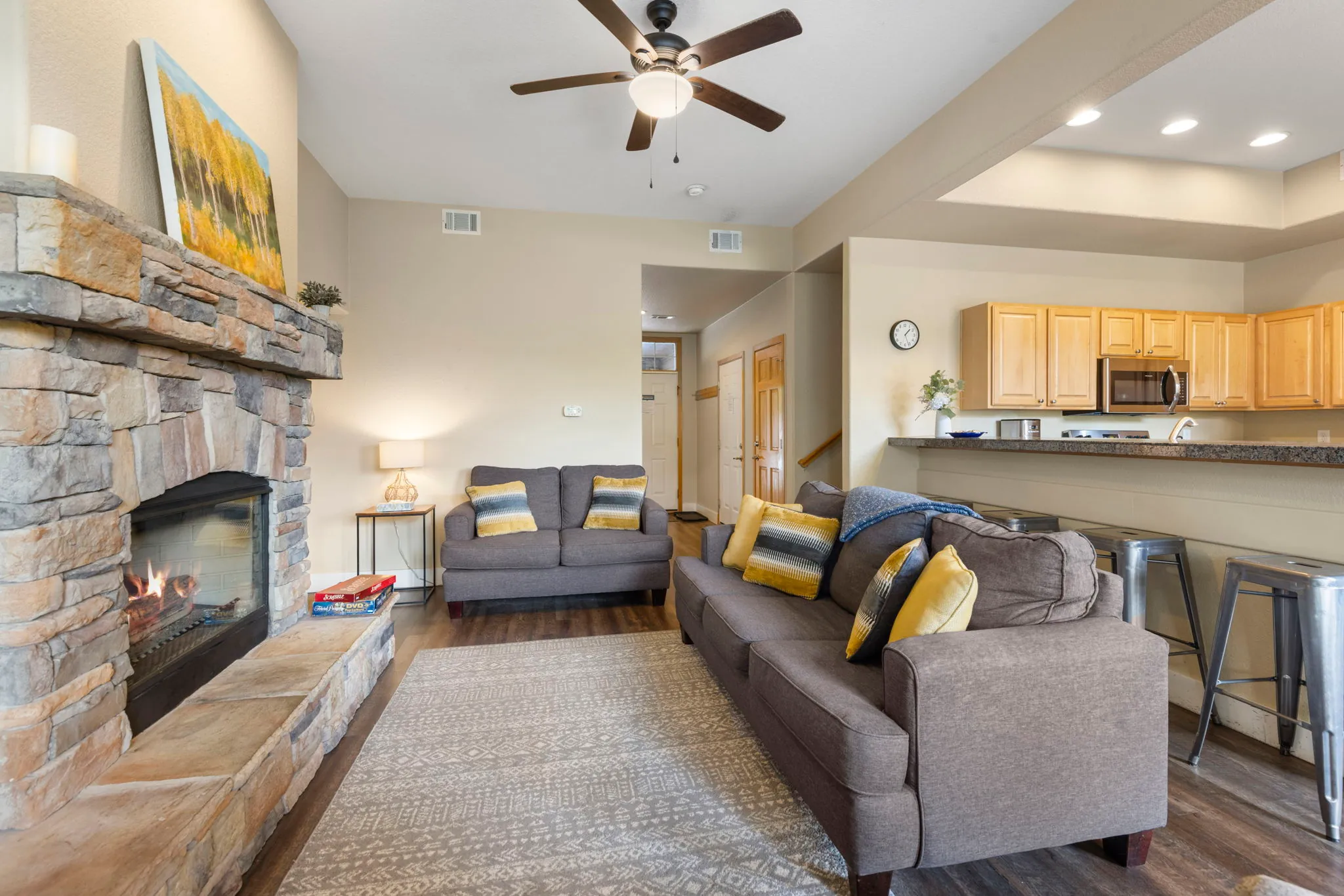North Pond Retreat, Living room sofas around the stone fireplace, with a serving tray and kitchen beyond, waterfront vacation rental in Silverthorne, Colorado