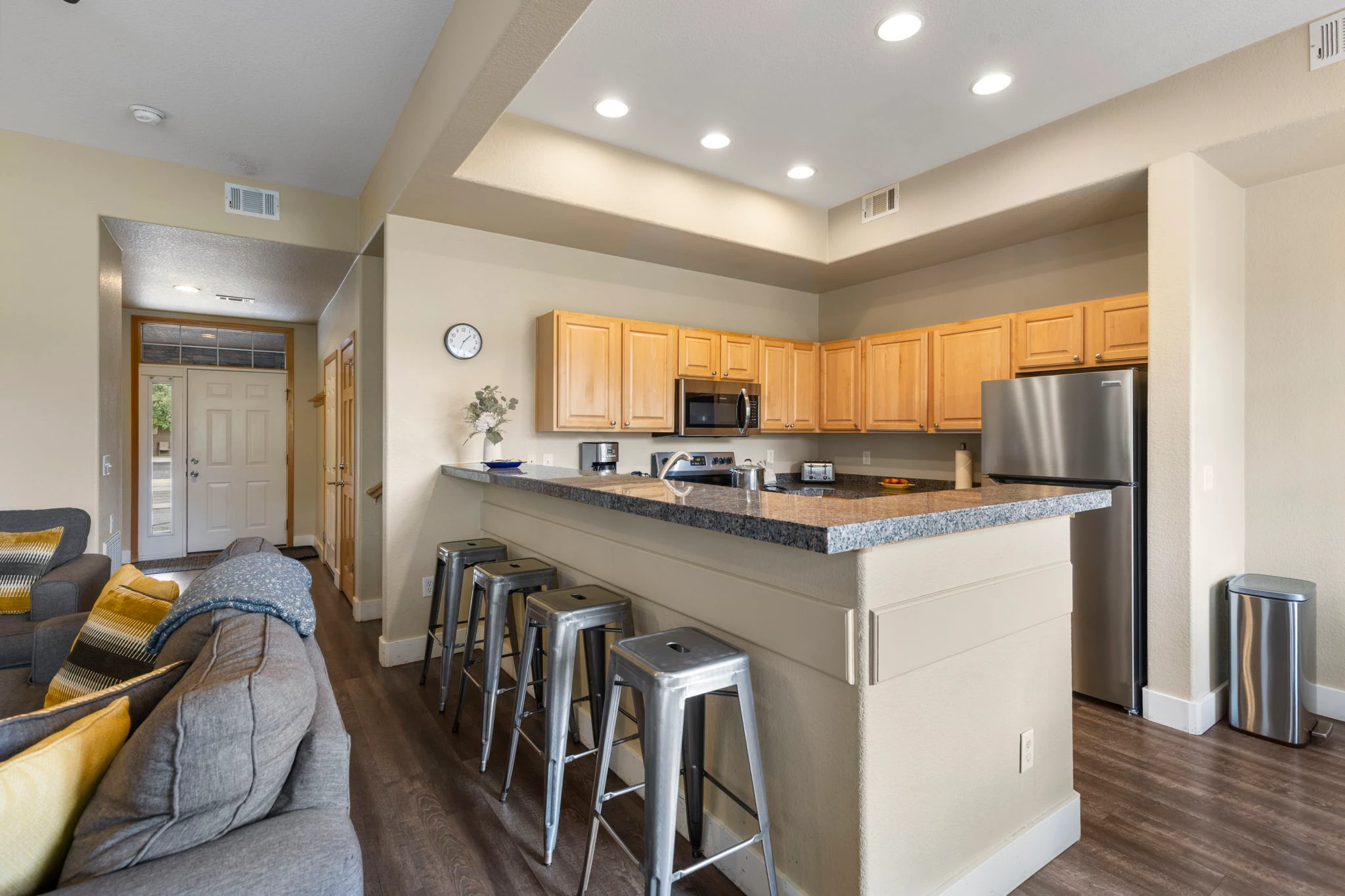 North Pond Retreat, Open kitchen with light wood cabinets, dark countertops, stainless appliances, and bar stools, waterfront vacation rental in Silverthorne, Colorado