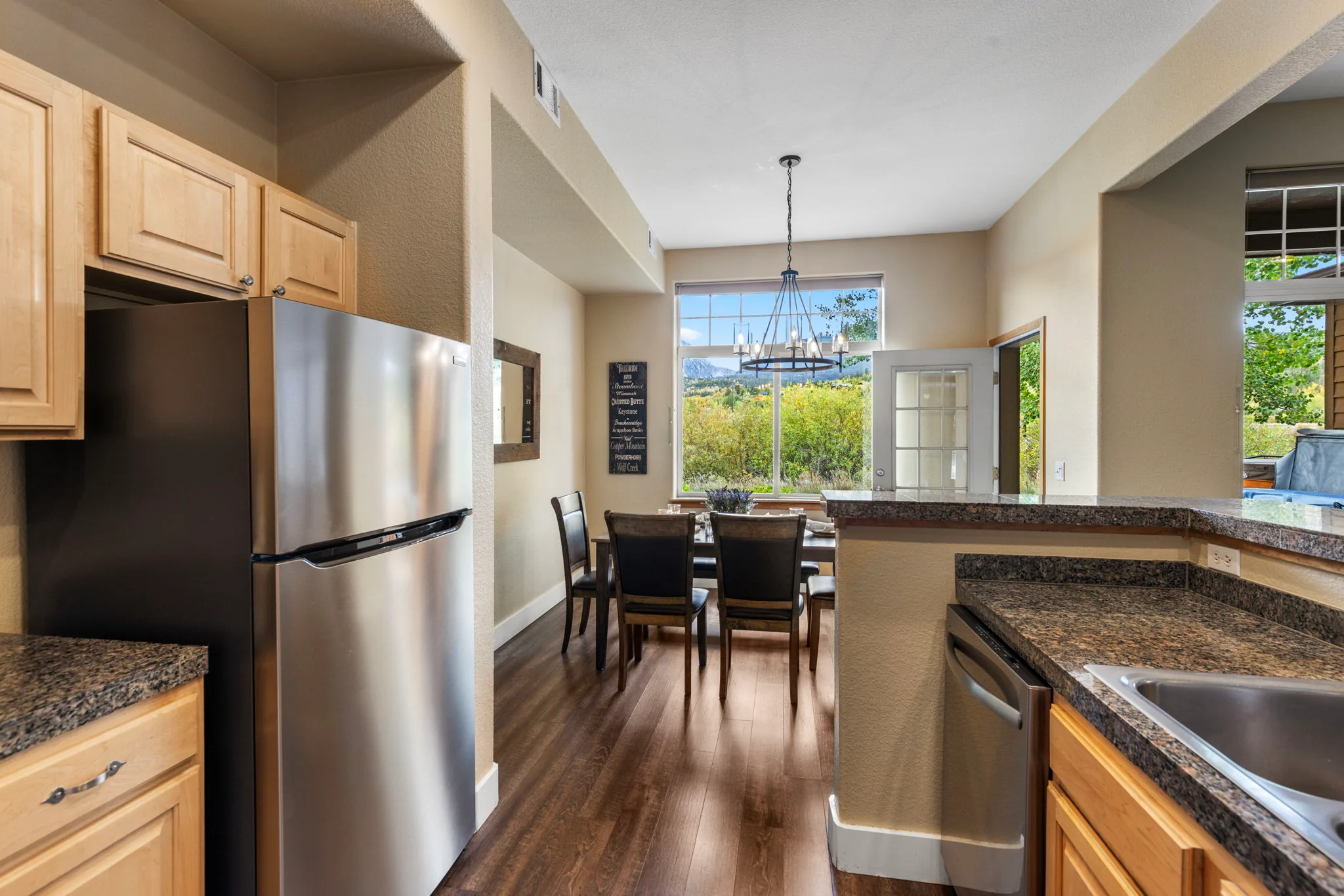 North Pond Retreat, Kitchen with stainless refrigerator and wood cabinetry beside the dining table and windows, waterfront vacation rental in Silverthorne, Colorado