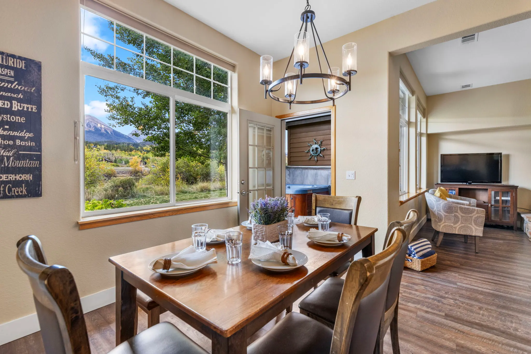 North Pond Retreat, Dining table with dishes, glasses, and chairs beside large windows and trees, waterfront vacation rental in Silverthorne, Colorado