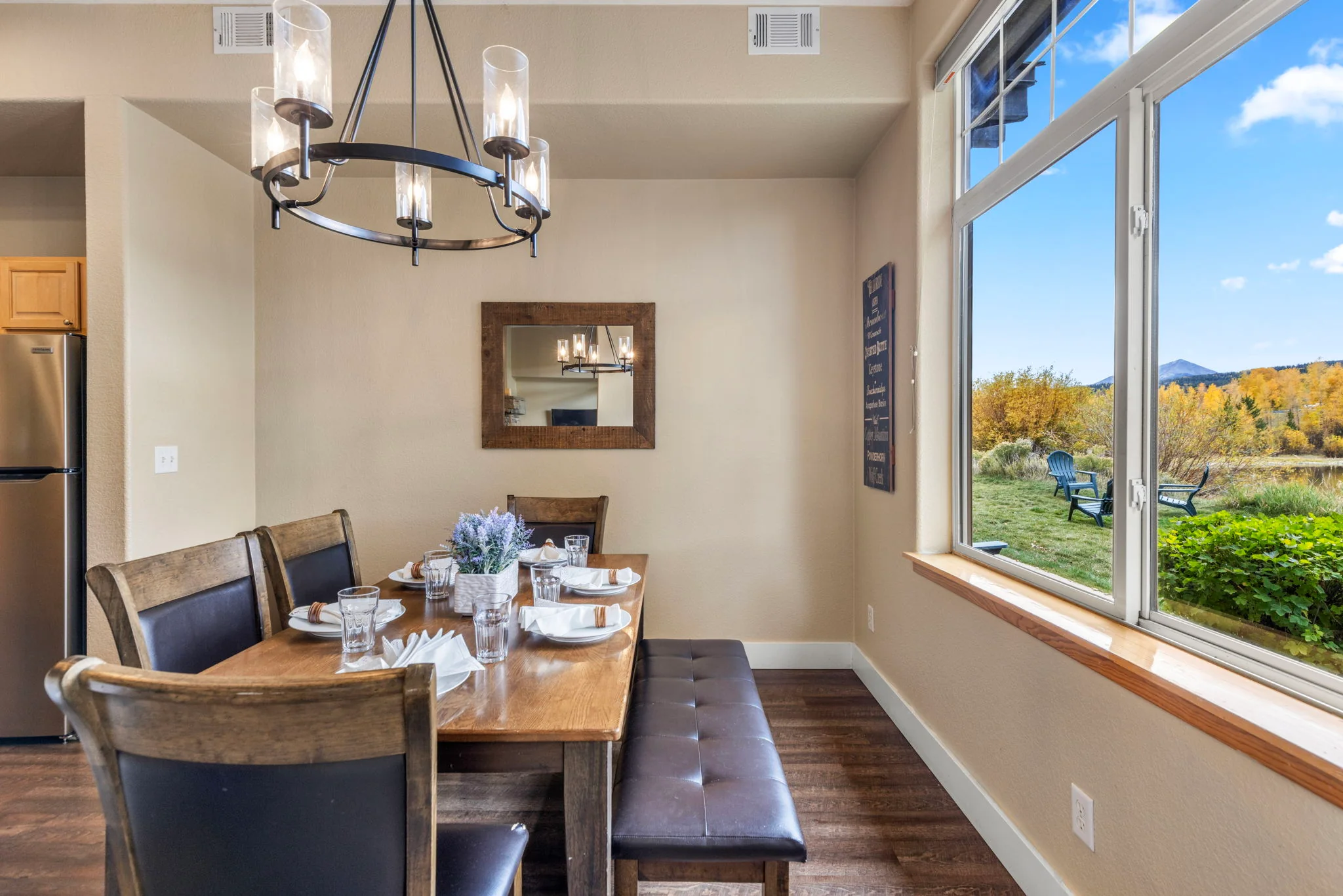 North Pond Retreat, Dining table with chairs and a bench beside large windows overlooking trees and mountains, waterfront vacation rental in Silverthorne, Colorado