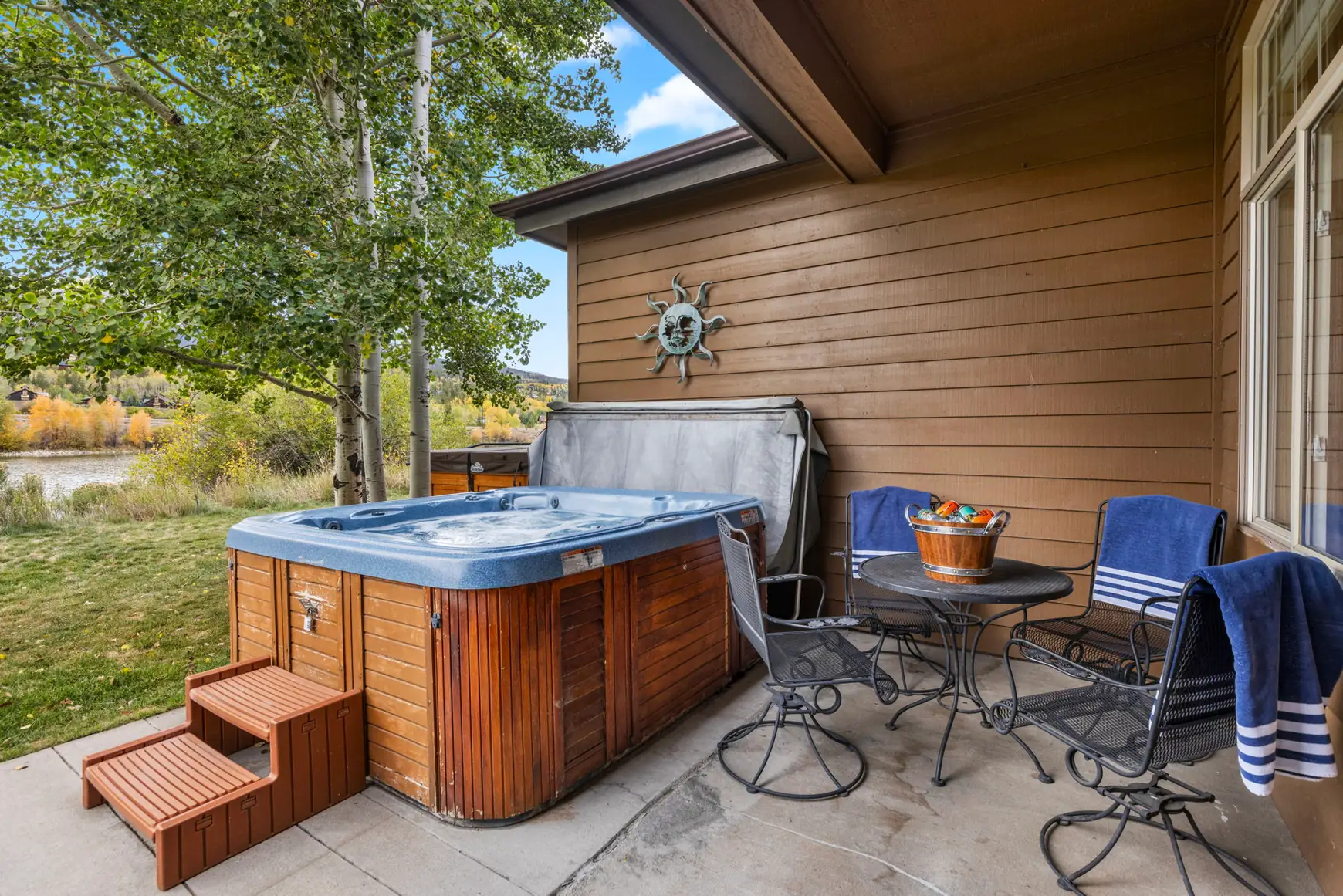 North Pond Retreat, Private patio with a hot tub, wooden steps, outdoor table, cushioned chairs, and sliding doors, waterfront vacation rental in Silverthorne, Colorado