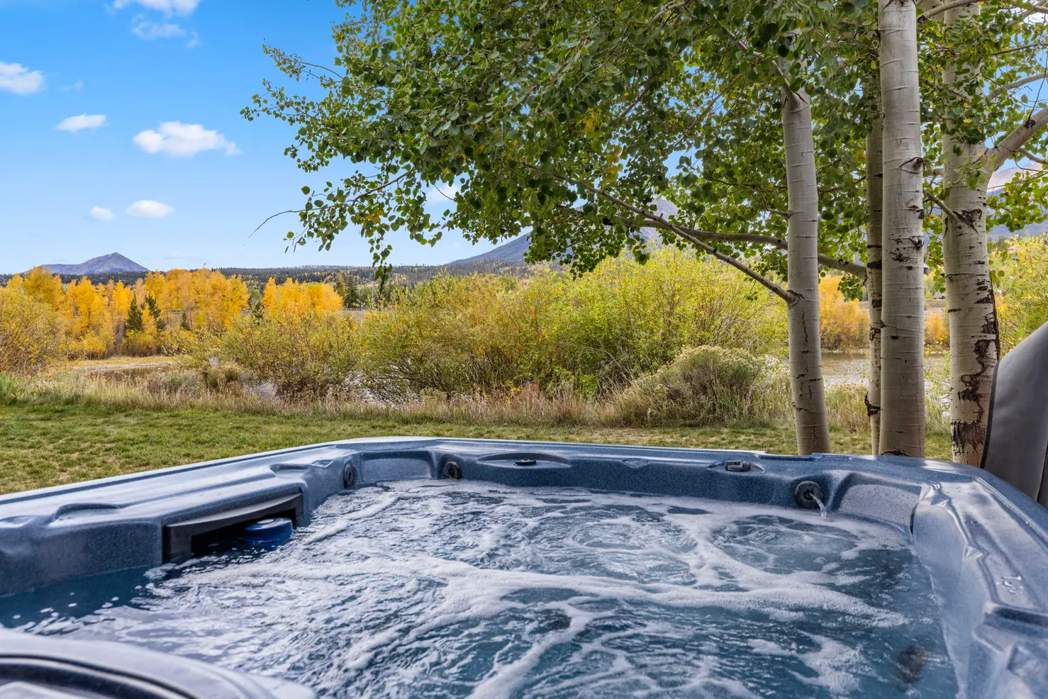 North Pond Retreat, Bubbling hot tub with trees, autumn grasses, and the waterfront setting beyond, waterfront vacation rental in Silverthorne, Colorado