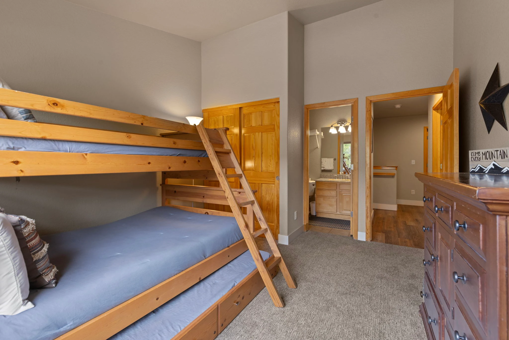 North Pond Retreat, Wood bunk bed and ladder with blue bedding, a dresser, and a wood doorway, waterfront vacation rental in Silverthorne, Colorado