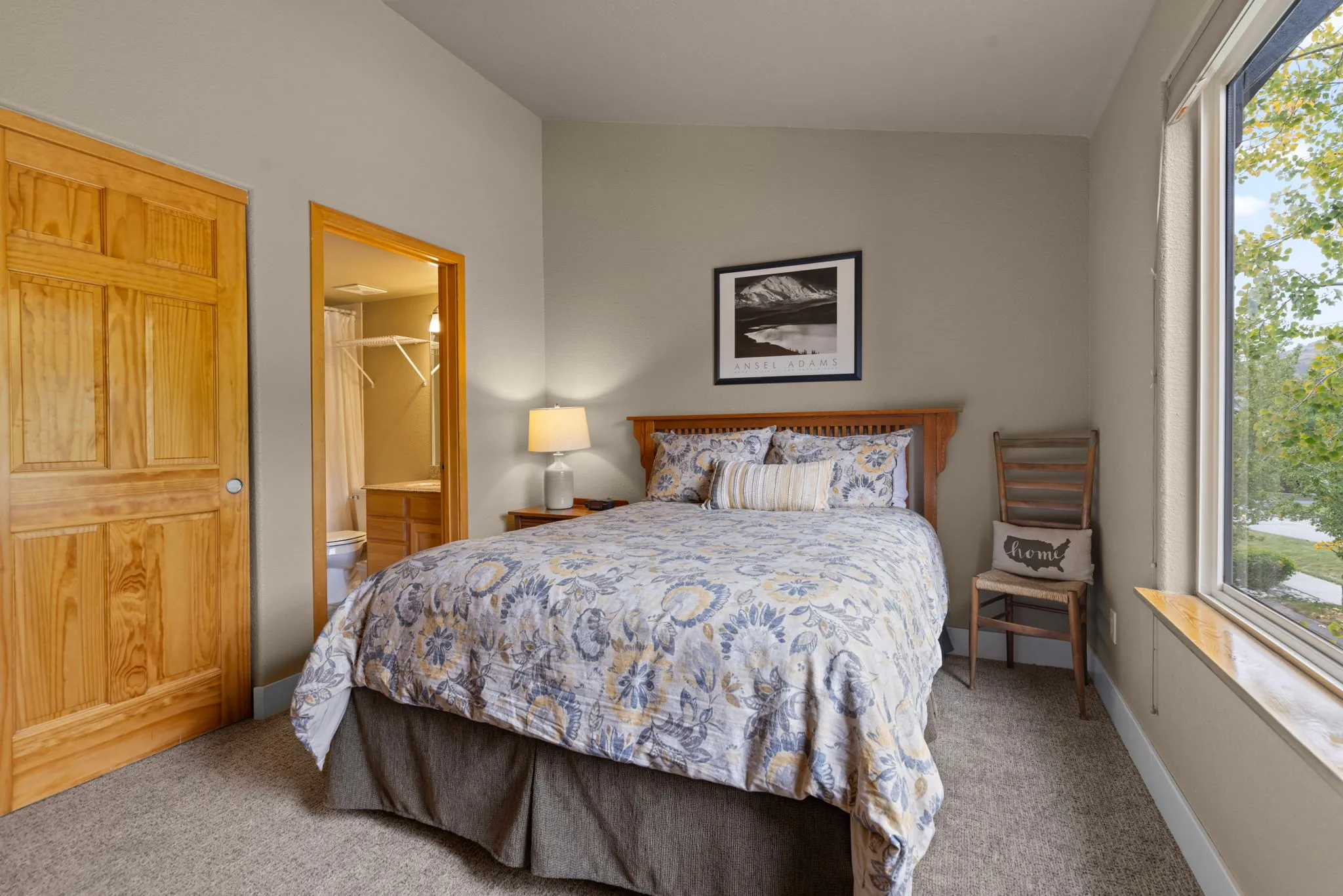 North Pond Retreat, Queen bedroom with patterned bedding, wood closet doors, mountain artwork, and a large window, waterfront vacation rental in Silverthorne, Colorado