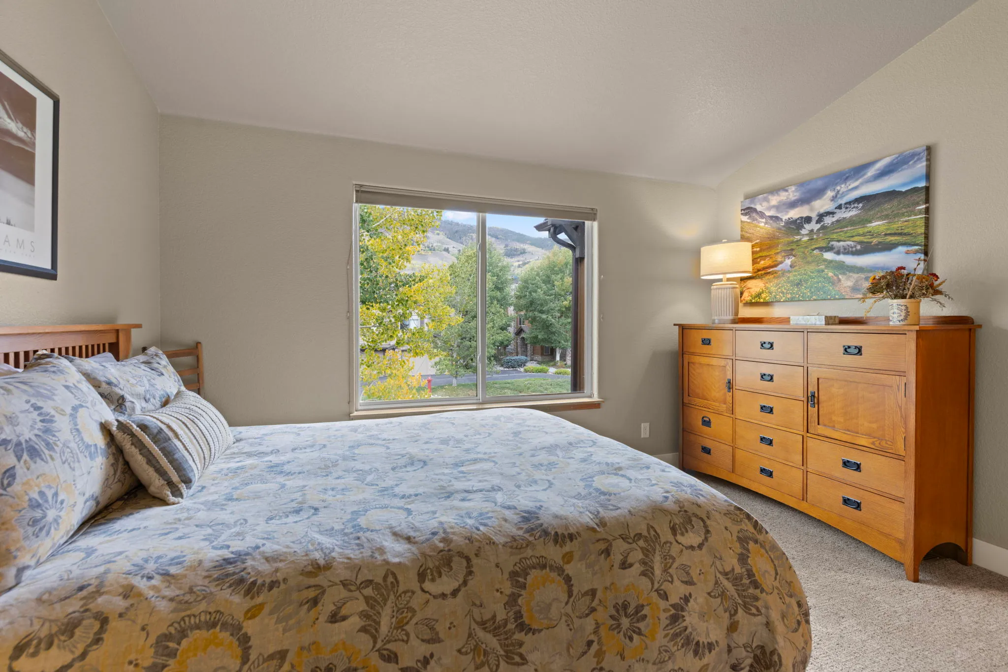 North Pond Retreat, Queen bed with a serving tray beside a wood dresser and window overlooking trees, waterfront vacation rental in Silverthorne, Colorado