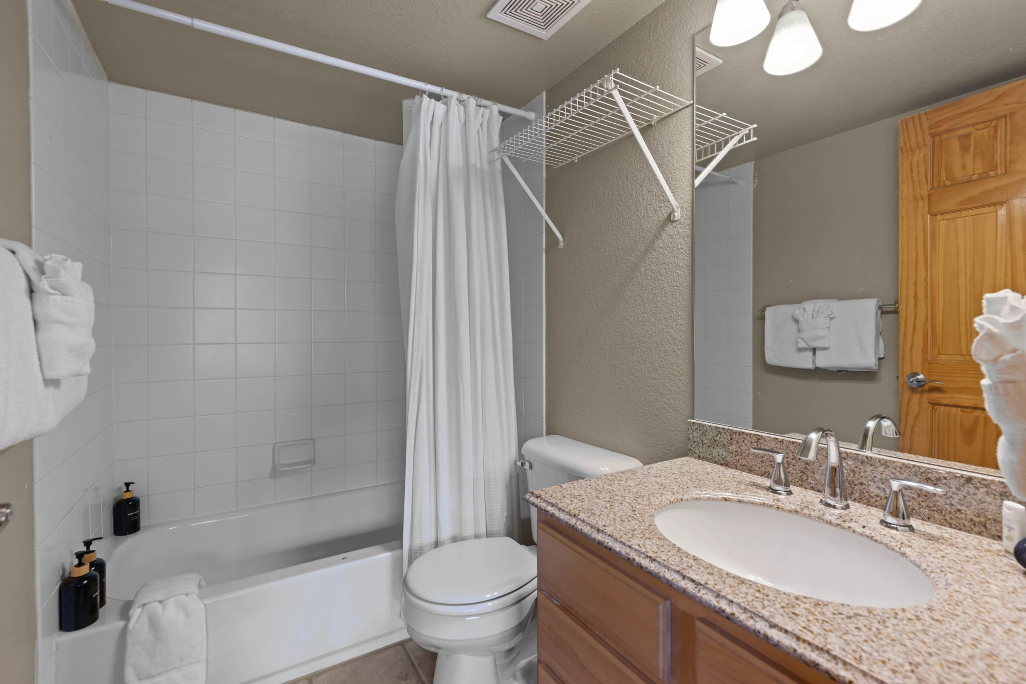 North Pond Retreat, Bathroom with a white shower curtain, bathtub, toilet, rounded vanity, and mirror, waterfront vacation rental in Silverthorne, Colorado