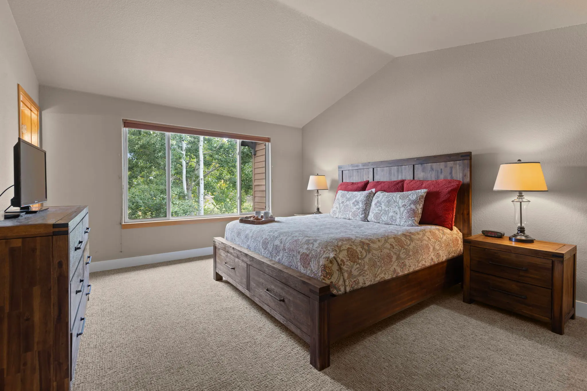 North Pond Retreat, King bedroom with a wood bed, large window, dresser, television, and bedside lamp, waterfront vacation rental in Silverthorne, Colorado