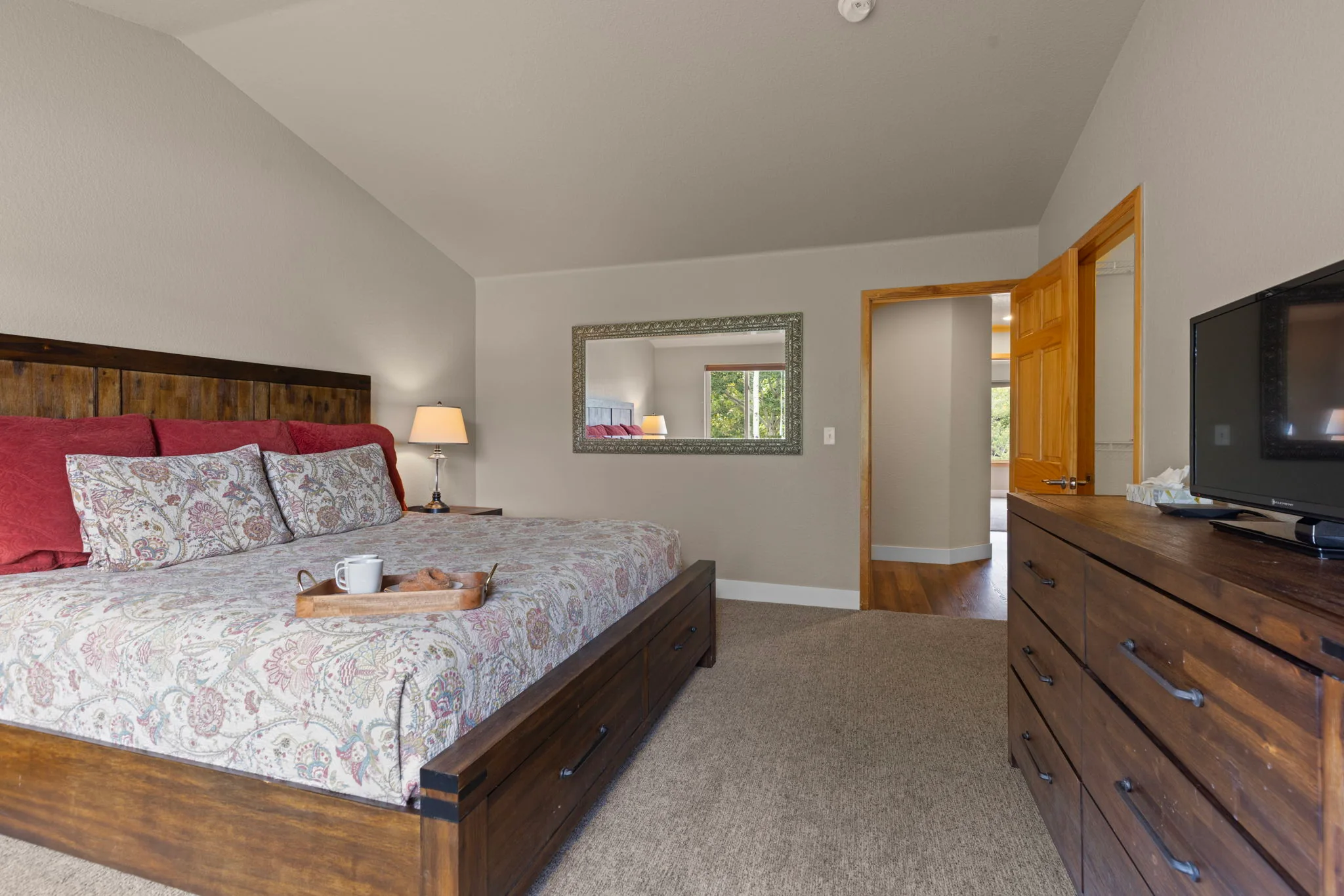 North Pond Retreat, King bedroom with a serving tray on the bed, dresser, television, lamp, and wall mirror, waterfront vacation rental in Silverthorne, Colorado