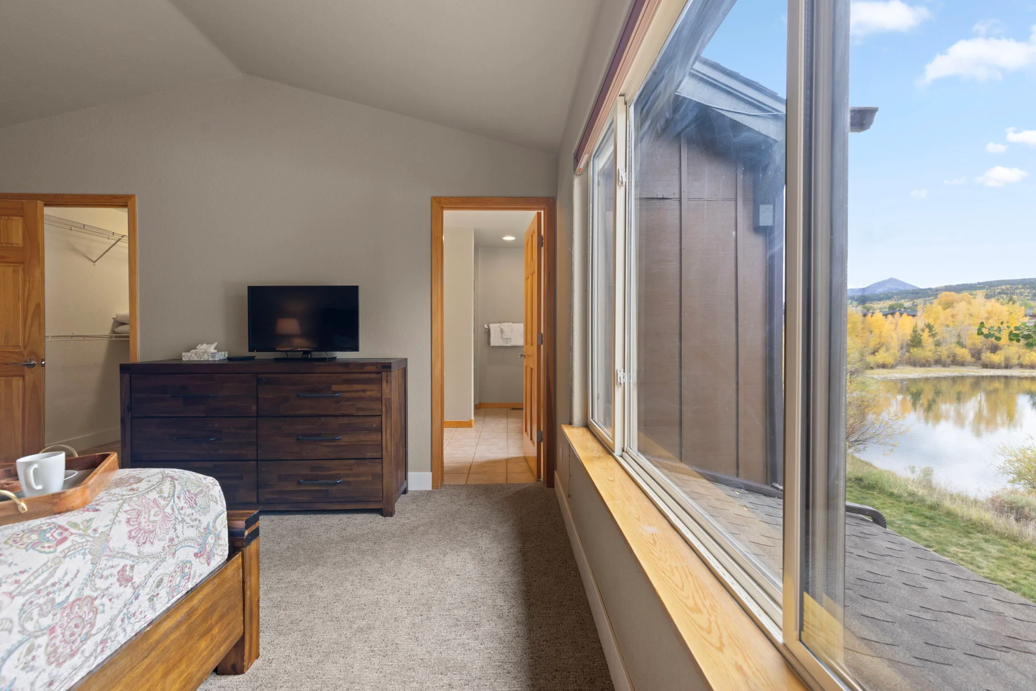 North Pond Retreat, Bedroom window overlooking the pond and mountains beside a dresser and television, waterfront vacation rental in Silverthorne, Colorado