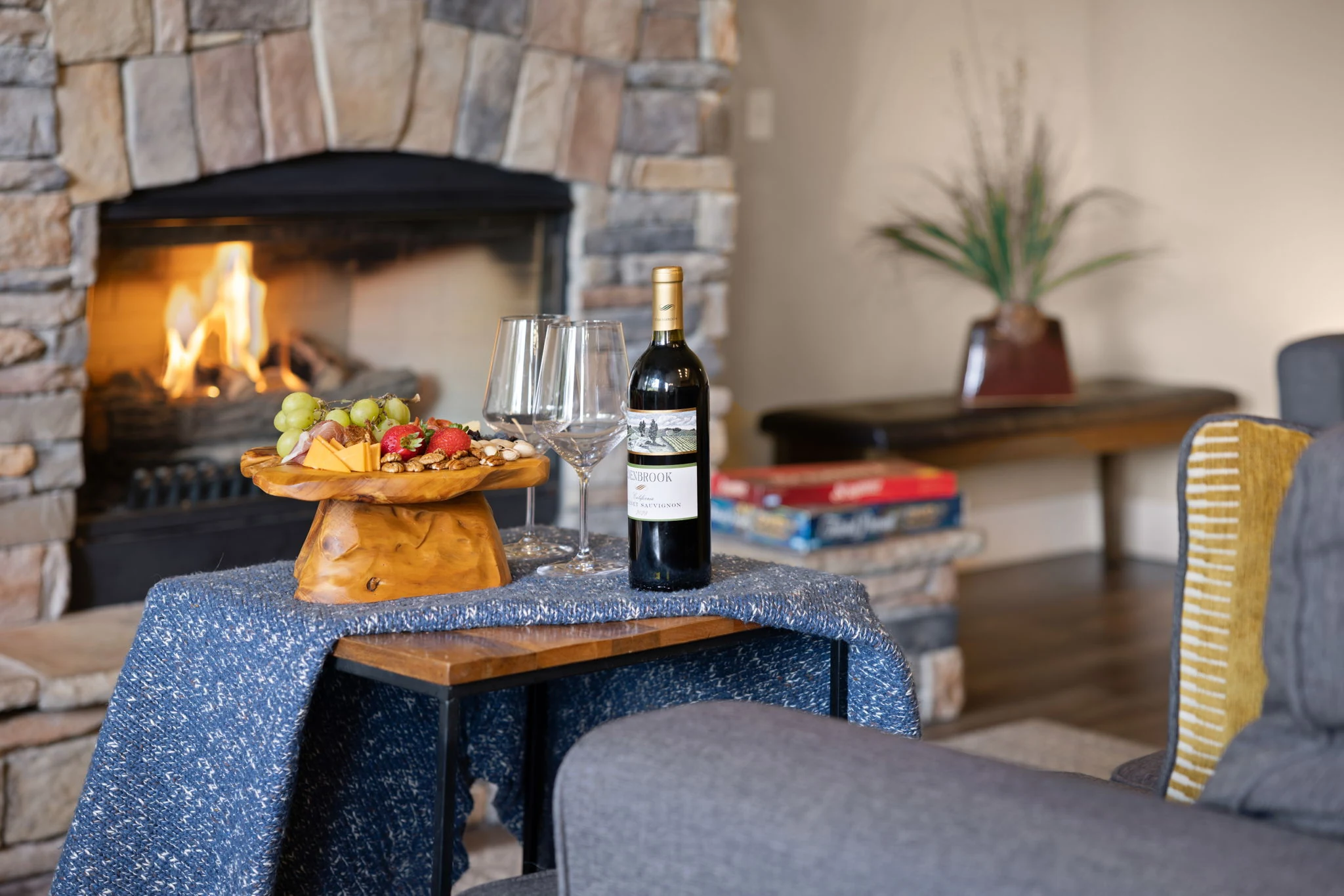 North Pond Retreat, Wine glasses, a bottle, and a cheese board beside the glowing stone fireplace, waterfront vacation rental in Silverthorne, Colorado